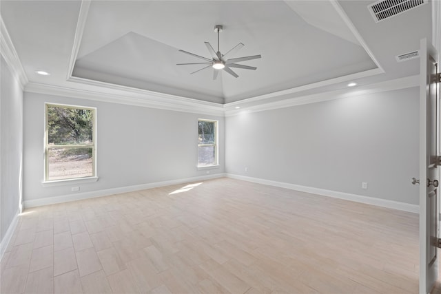 spare room with ceiling fan, a tray ceiling, light wood-type flooring, and plenty of natural light