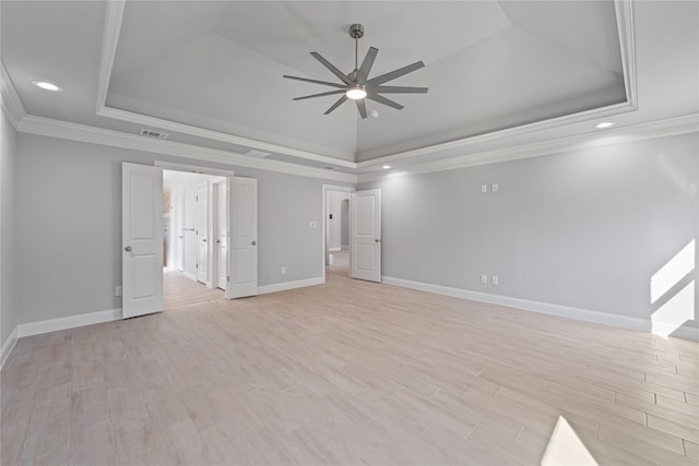 spare room with light hardwood / wood-style flooring, ornamental molding, a tray ceiling, and ceiling fan