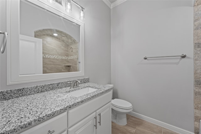 bathroom featuring toilet, ornamental molding, vanity, and a tile shower