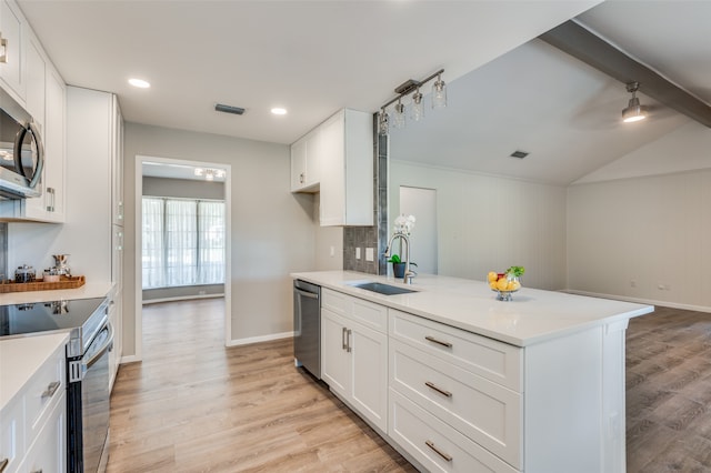 kitchen with appliances with stainless steel finishes, sink, vaulted ceiling with beams, white cabinetry, and light hardwood / wood-style flooring