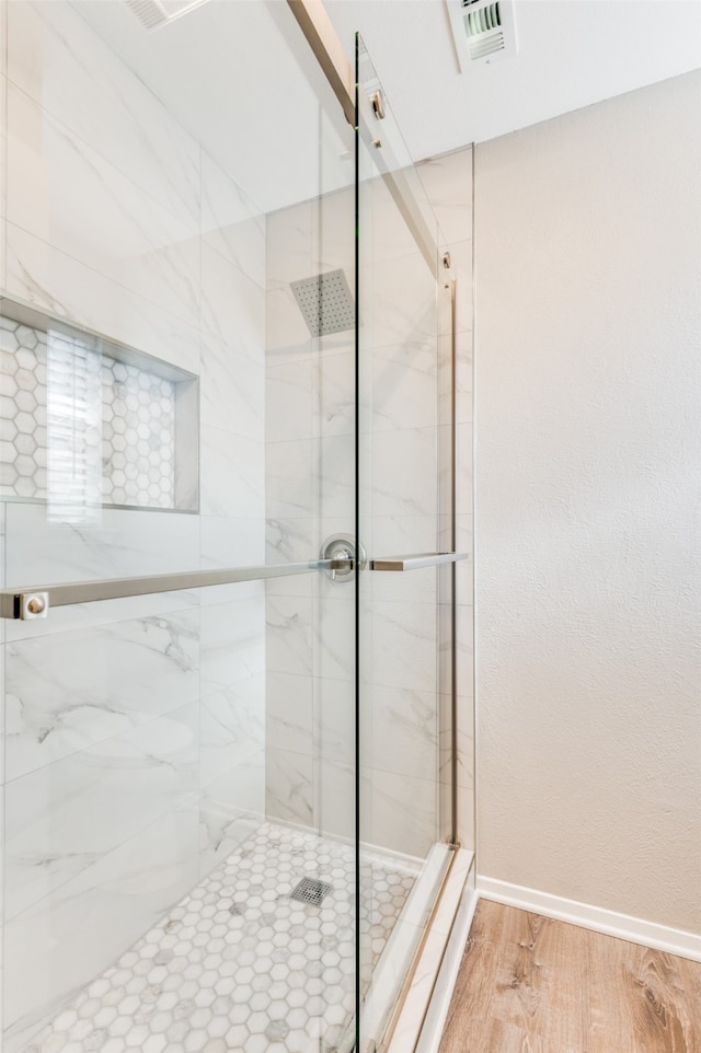 bathroom featuring hardwood / wood-style flooring and walk in shower