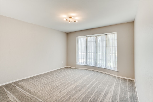 carpeted empty room with a chandelier