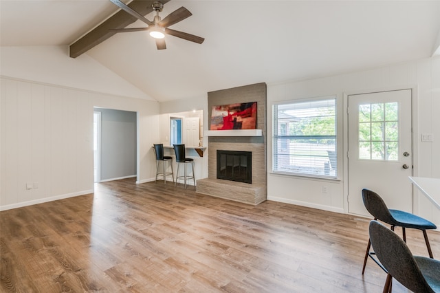 unfurnished living room with hardwood / wood-style floors, vaulted ceiling with beams, a fireplace, and ceiling fan