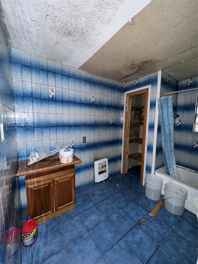 bathroom with shower / bath combo with shower curtain, heating unit, tile walls, and tile patterned flooring