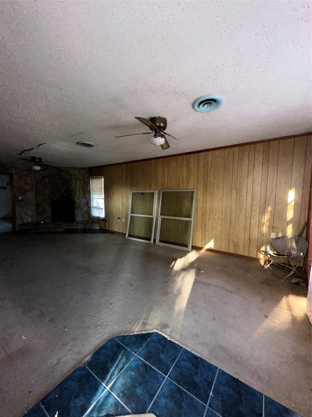 interior space featuring wooden walls, a textured ceiling, and ceiling fan