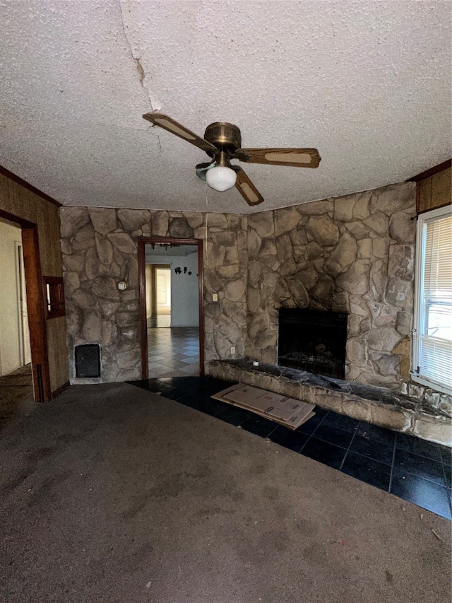 unfurnished living room with dark carpet, a textured ceiling, a fireplace, and ceiling fan