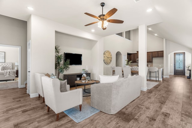 living room featuring light hardwood / wood-style flooring, high vaulted ceiling, and ceiling fan