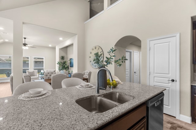 kitchen featuring light stone counters, ceiling fan, light wood-type flooring, dishwasher, and sink