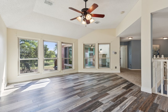 unfurnished living room with a textured ceiling, dark wood-type flooring, and vaulted ceiling