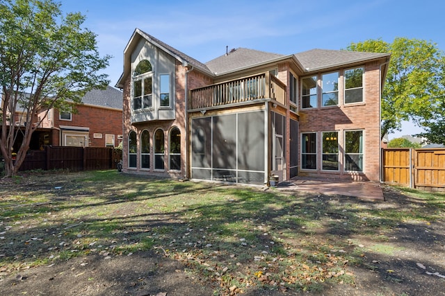 rear view of property featuring a balcony, a yard, and a patio area