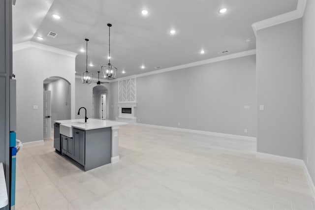 kitchen featuring a center island with sink, ornamental molding, pendant lighting, gray cabinetry, and sink