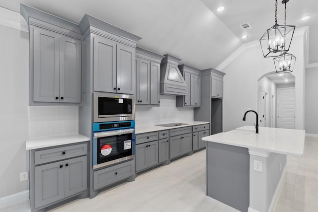 kitchen featuring tasteful backsplash, appliances with stainless steel finishes, lofted ceiling, custom exhaust hood, and gray cabinets