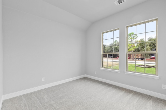 carpeted spare room featuring vaulted ceiling