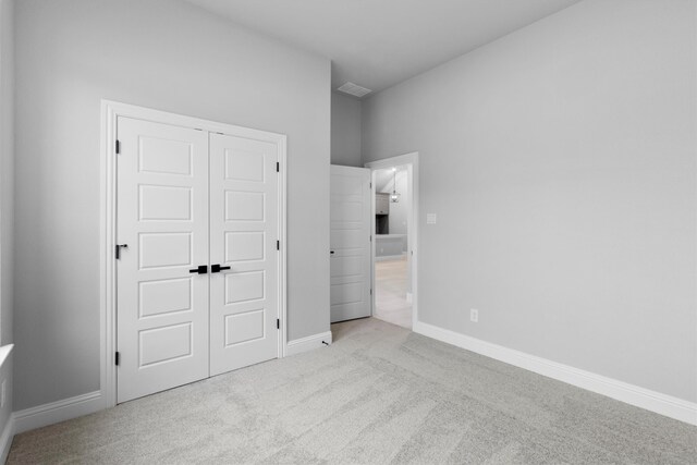 unfurnished bedroom featuring light colored carpet and a closet