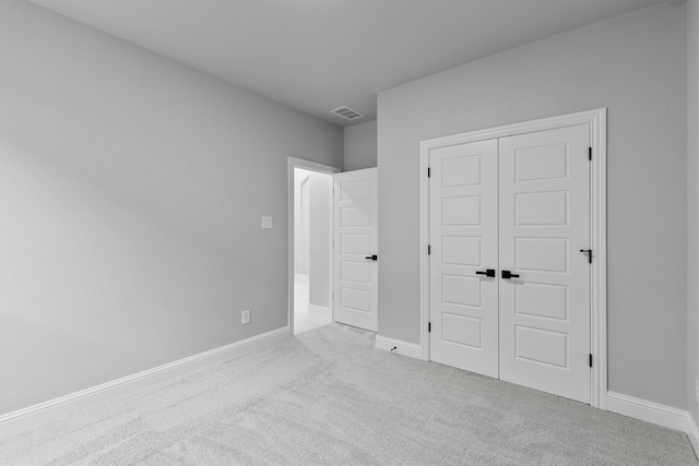 unfurnished bedroom featuring light carpet and a closet