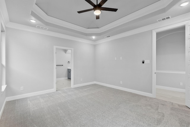 unfurnished bedroom with ensuite bathroom, a raised ceiling, ceiling fan, ornamental molding, and light colored carpet