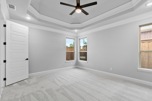 carpeted empty room with crown molding, a tray ceiling, and ceiling fan