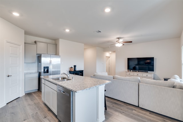 kitchen with sink, an island with sink, light hardwood / wood-style floors, stainless steel appliances, and ceiling fan