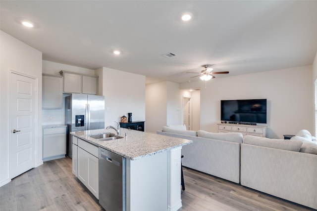 723 Cherish Day Dr, Lavon, TX 75166 - kitchen featuring appliances with stainless steel finishes, a sink, open floor plan, a ceiling fan, and light wood finished floors