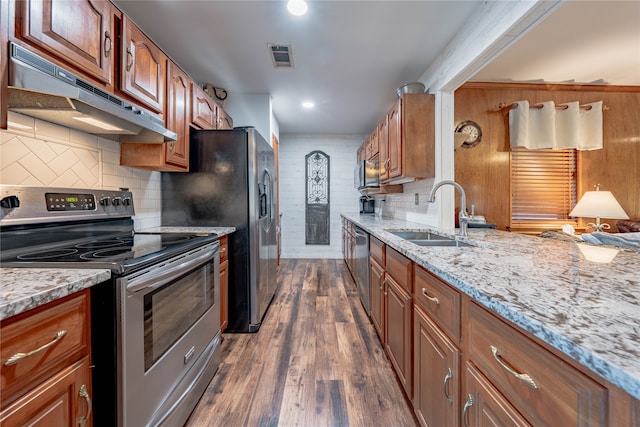 kitchen featuring appliances with stainless steel finishes, light stone countertops, sink, and dark wood-type flooring