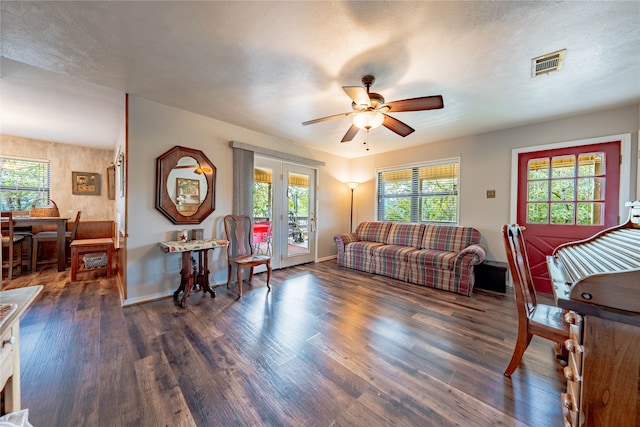 living room with a wealth of natural light, a textured ceiling, dark hardwood / wood-style floors, and ceiling fan