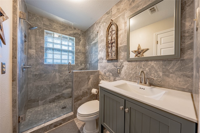 bathroom featuring vanity, toilet, walk in shower, and tile walls