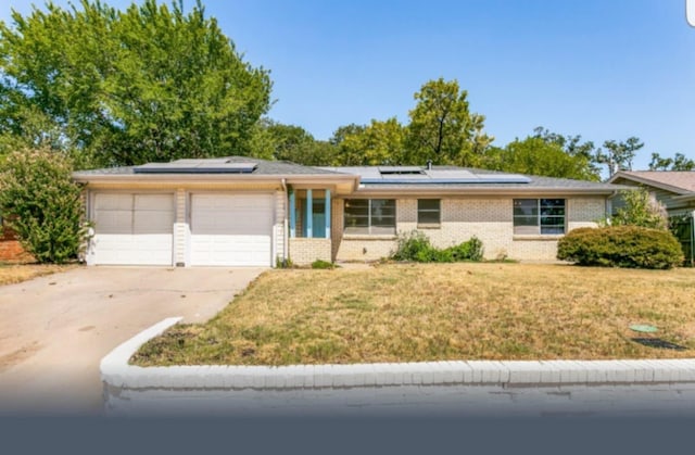 ranch-style home featuring solar panels, a garage, and a front lawn