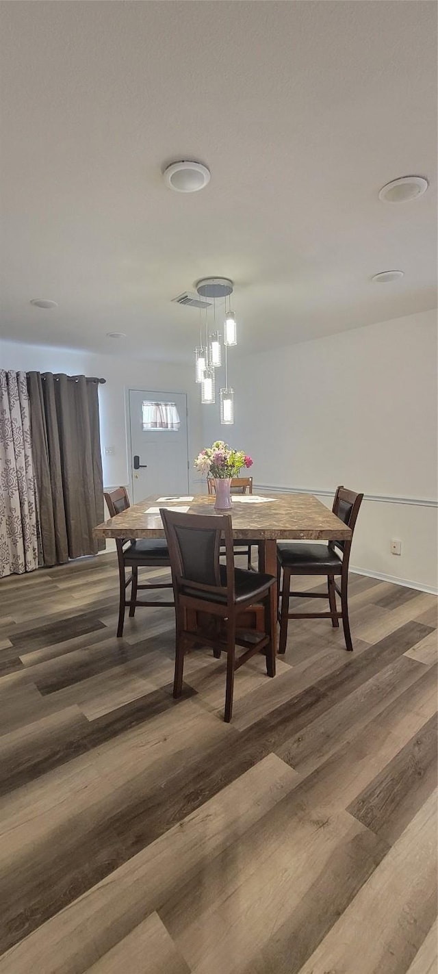 dining space with wood-type flooring and an inviting chandelier