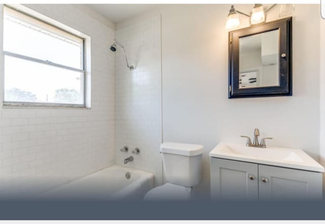 full bathroom featuring vanity, tiled shower / bath combo, and toilet