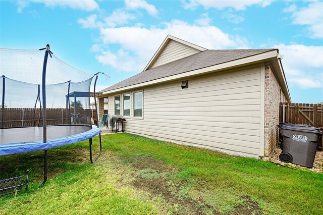 rear view of house with a yard and a trampoline