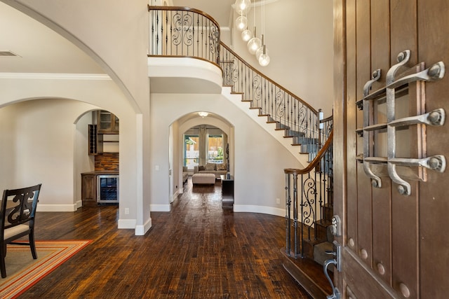 foyer entrance featuring a high ceiling, ornamental molding, and dark hardwood / wood-style floors