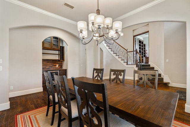 dining area with dark wood-type flooring, a notable chandelier, and crown molding