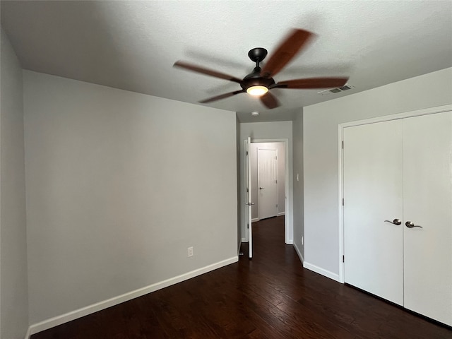 unfurnished bedroom with dark wood-type flooring, ceiling fan, a closet, and a textured ceiling