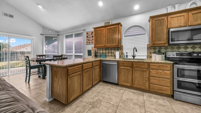 kitchen with lofted ceiling, appliances with stainless steel finishes, kitchen peninsula, and tasteful backsplash