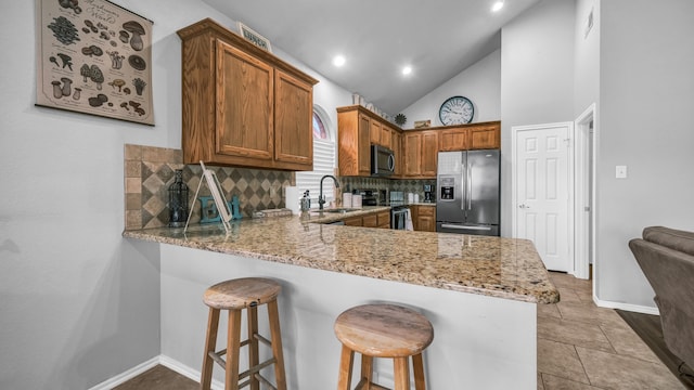 kitchen with sink, light stone countertops, decorative backsplash, and stainless steel appliances