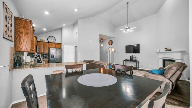 dining room featuring ceiling fan, high vaulted ceiling, and dark hardwood / wood-style floors