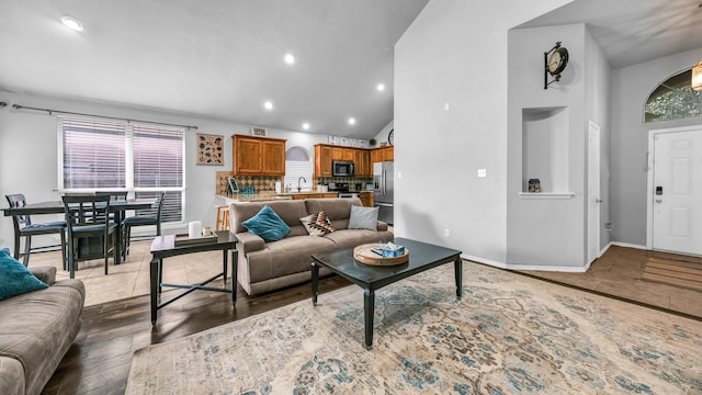 living room with sink, dark hardwood / wood-style floors, and high vaulted ceiling