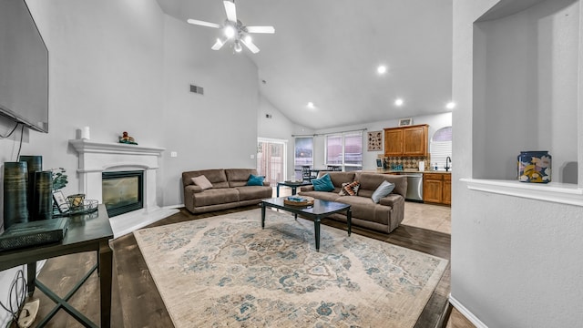 living room featuring light hardwood / wood-style flooring, high vaulted ceiling, and ceiling fan