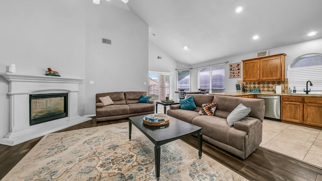 living room with light hardwood / wood-style flooring, high vaulted ceiling, and sink