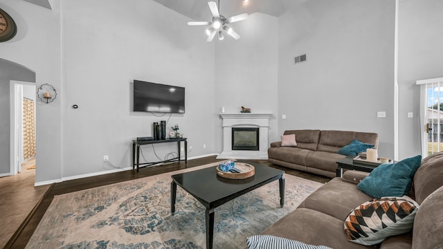 living room with dark wood-type flooring, ceiling fan, and high vaulted ceiling