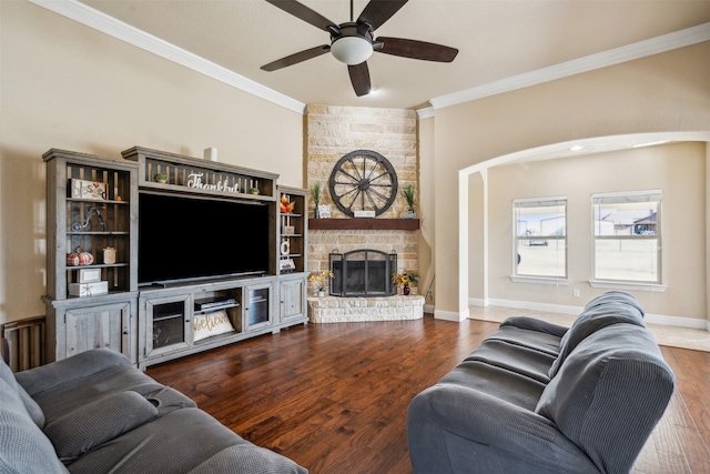 living room with crown molding, dark wood-type flooring, a fireplace, and ceiling fan