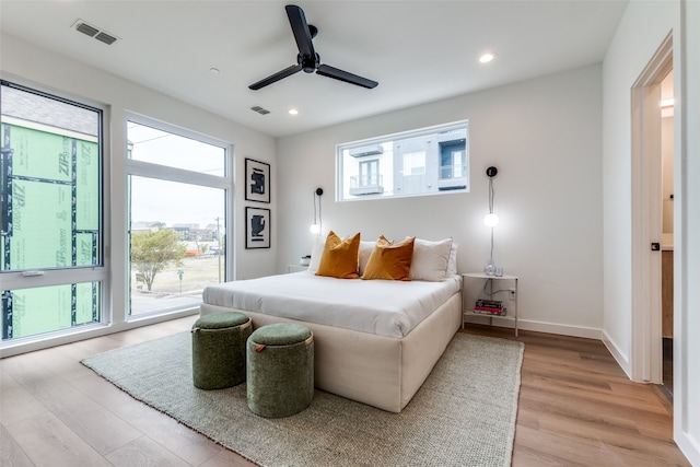 bedroom featuring ceiling fan, multiple windows, light wood-type flooring, and access to exterior