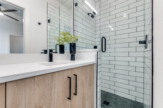 bathroom with vanity, a shower with shower door, and ceiling fan