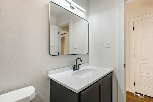 bathroom with vanity, toilet, and wood-type flooring