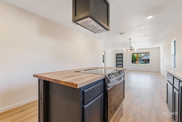 kitchen with stainless steel electric stove, a chandelier, light wood-type flooring, butcher block counters, and a center island