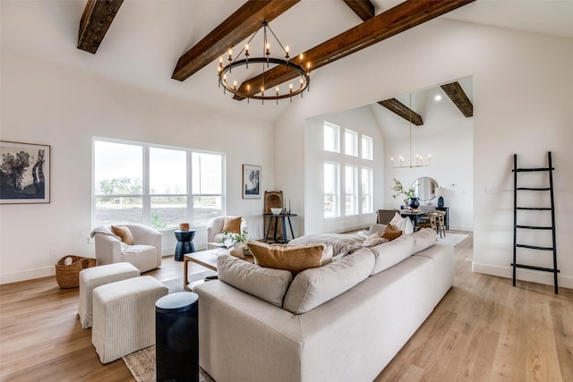 living room featuring plenty of natural light, light hardwood / wood-style flooring, beamed ceiling, and an inviting chandelier