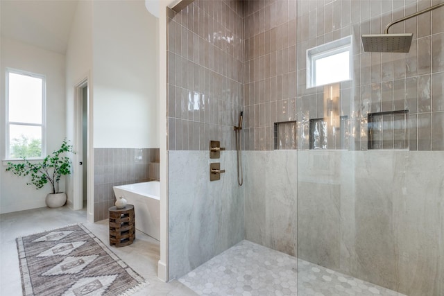 bathroom with tile walls, shower with separate bathtub, and a healthy amount of sunlight