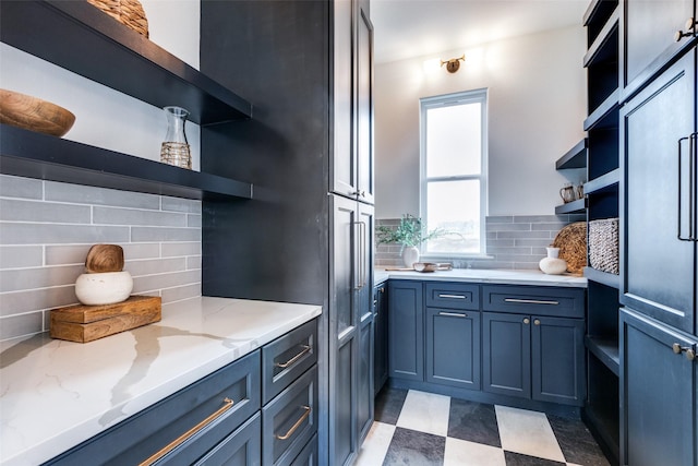 kitchen with backsplash, light stone countertops, and blue cabinets