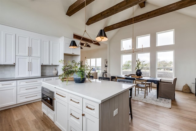 kitchen featuring decorative light fixtures, decorative backsplash, built in microwave, and white cabinetry