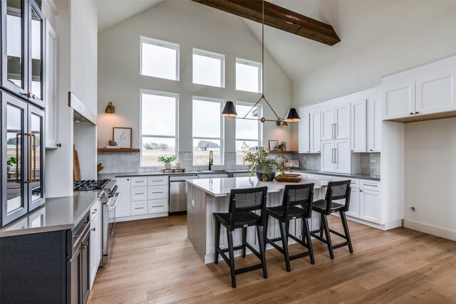 kitchen featuring decorative backsplash, sink, white cabinetry, appliances with stainless steel finishes, and a breakfast bar area